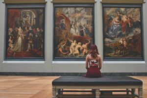 Schreiben im Museum - Eine Frau sitzt im Museum vor einem Gemälde